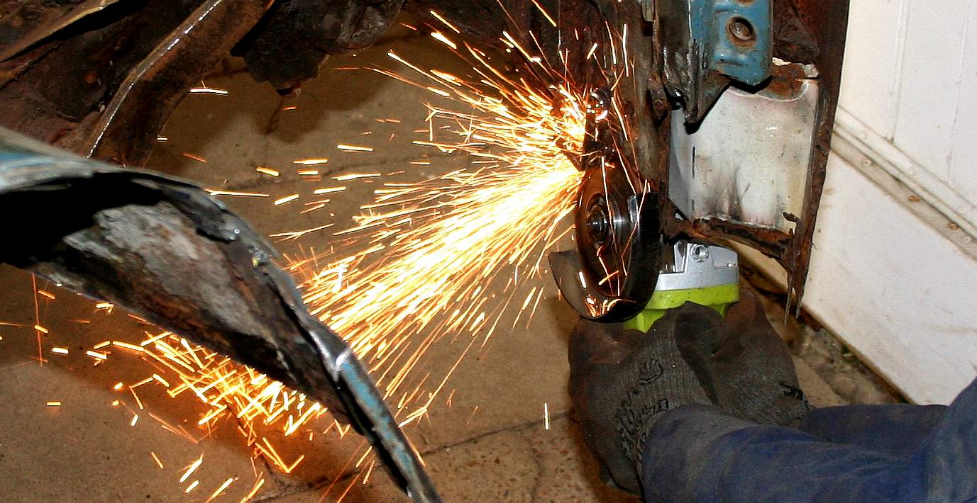 Using an angle grinder to cut out the rusted sections